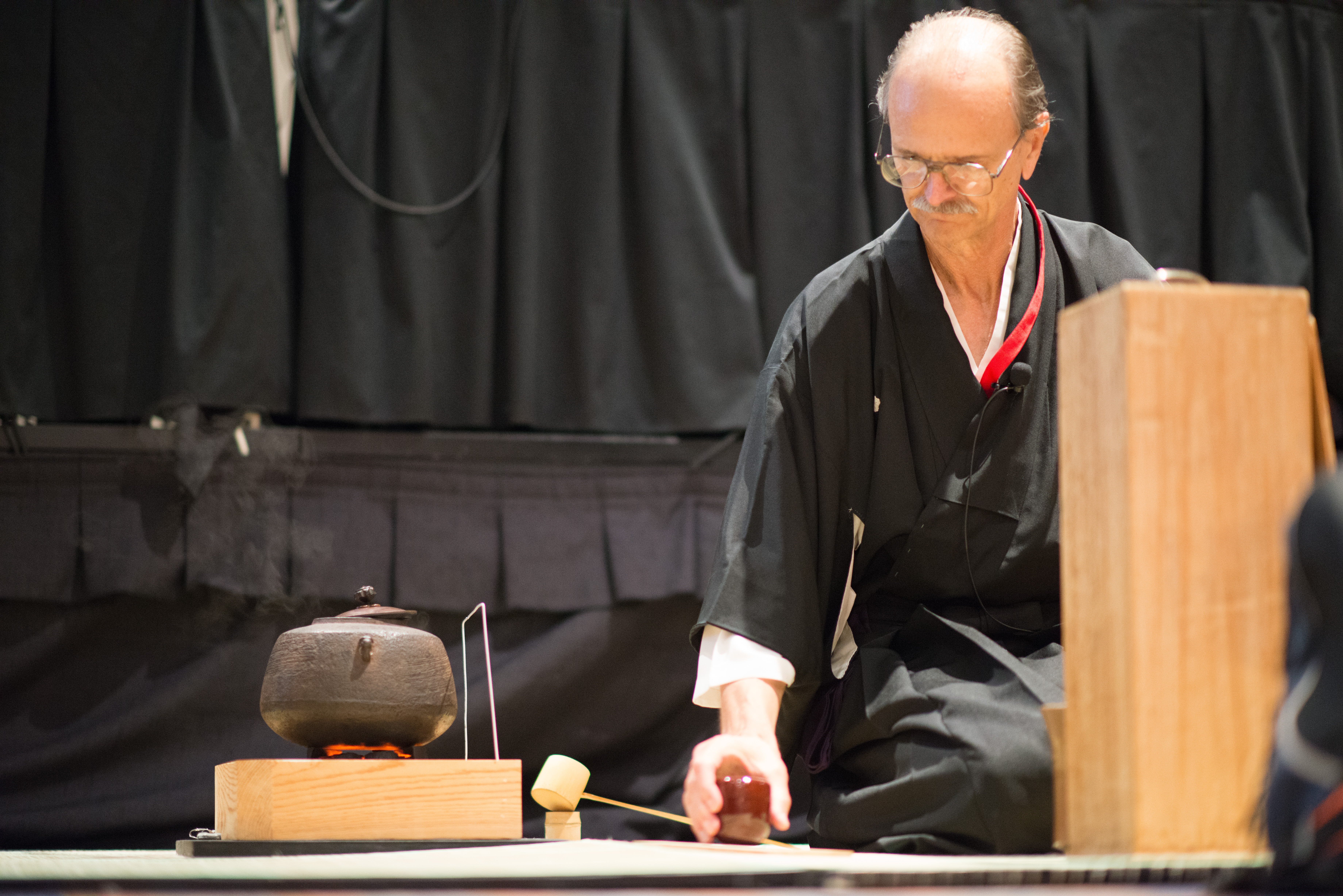 a man in traditional Japanese clothing performing a tea ceremony