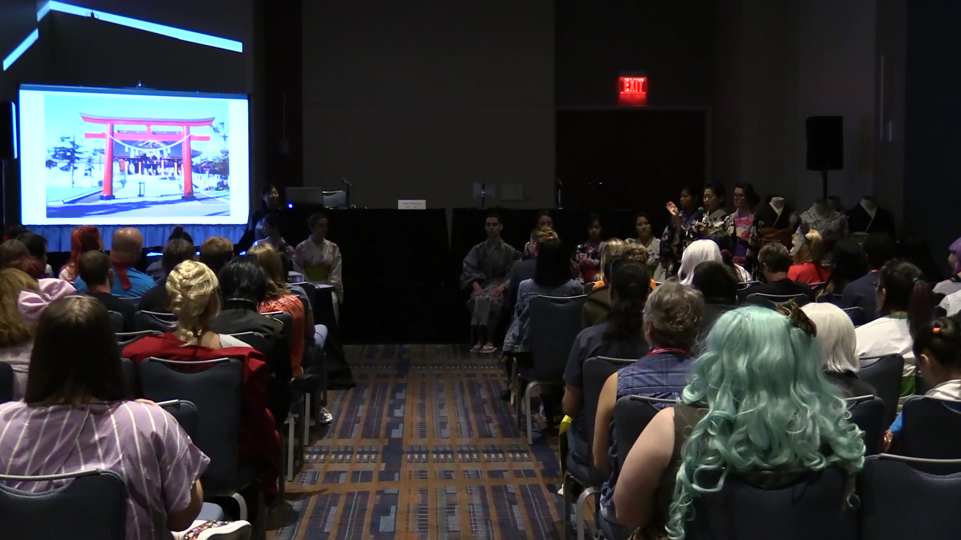 guests seated in a dimly lit panel room learning about Japan