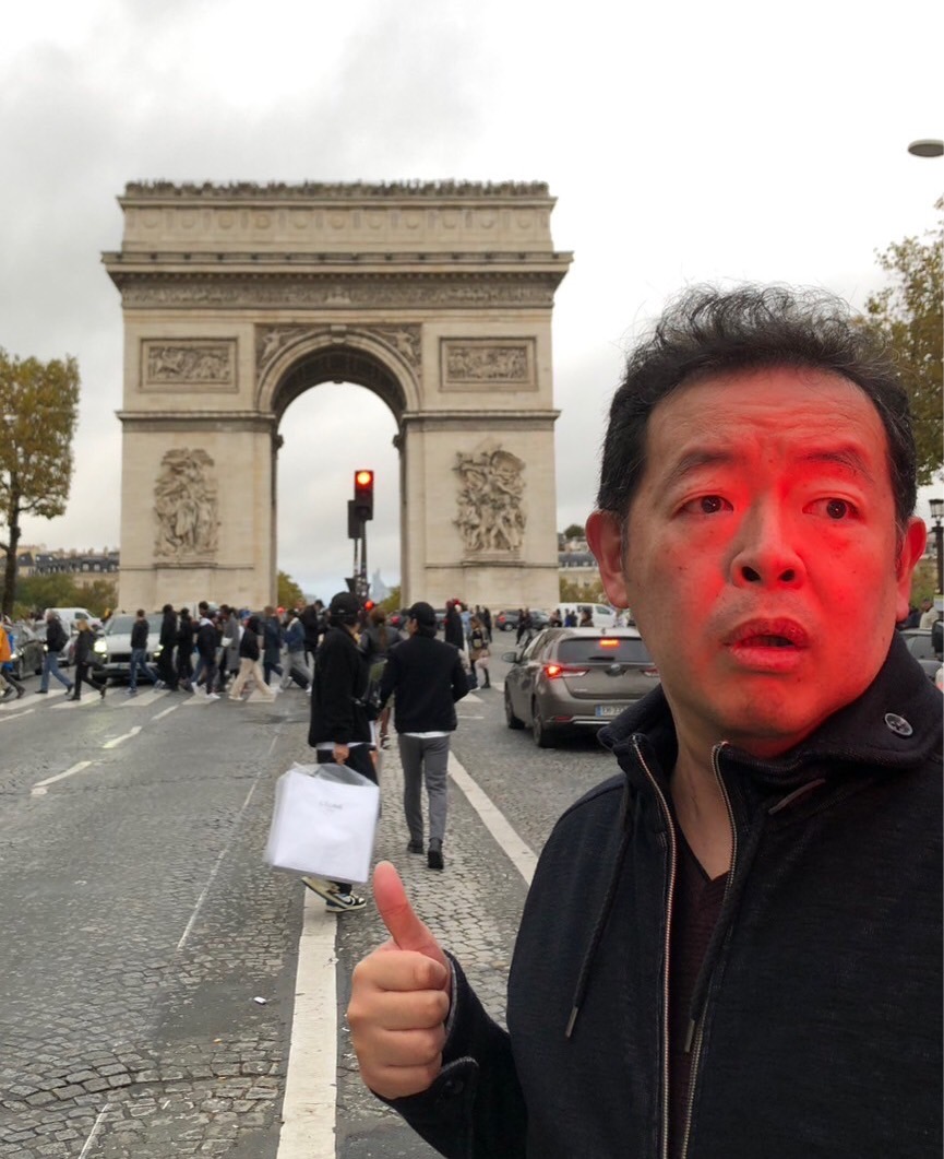 a casual photo of Hiroshi Nagahama with the Arc de Triomphe in the background